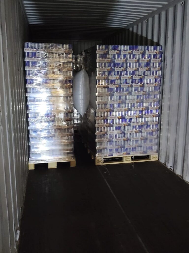 Two rows of wrapped energy drink pallets braced with air bags in a trailer for a vending route delivery